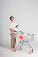 Smiling woman happily pushing a supermarket cart, isolated on white background