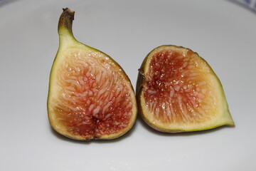 Fresh slice of fig lying on a heap of ripe figs. Heap of tasty organic figs