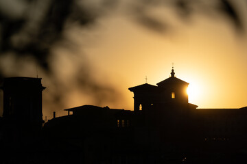 a church with a sun shining behind it and a silhouette