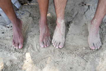The feet of two brown men on the beach sand. feet dirty with sand
