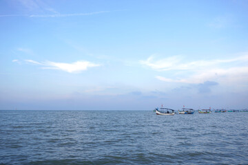 Morning on the beach with clear skies, small waves passing by the boat, and there is a boat parked on the beach
