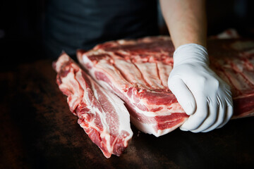 Hands cutting raw meat, chunks of pork