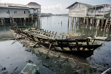photo of a small wooden boat in disrepair with garbage scattered on the shorephotos of small wooden...