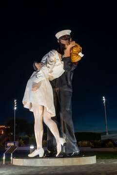 San Diego, California, USA - January 24, 2024: Giant Sailor Statue Embracing Nurse Girlfriend War Monument Night Portrait by USS Midway Harbour Maritime Museum