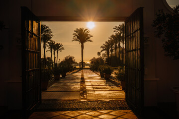 Sotogrante, Spain - January 27, 2024 - an open gate with a view of palm trees and a sunset in the...