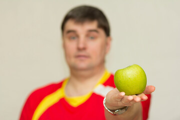 young handsome man holding a green apple in his hands