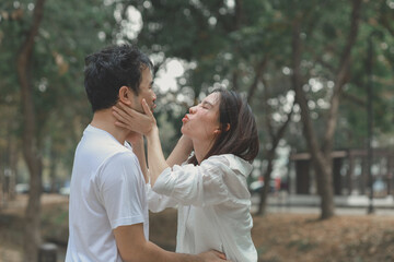 Fototapeta premium Happy young Asian couple in a park, Portrait of smiling couple near beautiful nature outdoors, lifestyle, Cheerful couple hugging each other, Young couple enjoying the sunny day at park