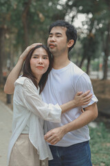 Obraz premium Happy young Asian couple in a park, Portrait of smiling couple near beautiful nature outdoors, lifestyle, Cheerful couple hugging each other, Young couple enjoying the sunny day at park
