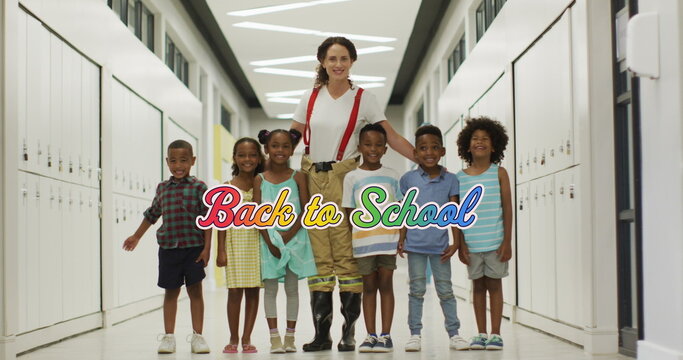 Image of back to school text in rainbow colours over happy diverse female teacher and children