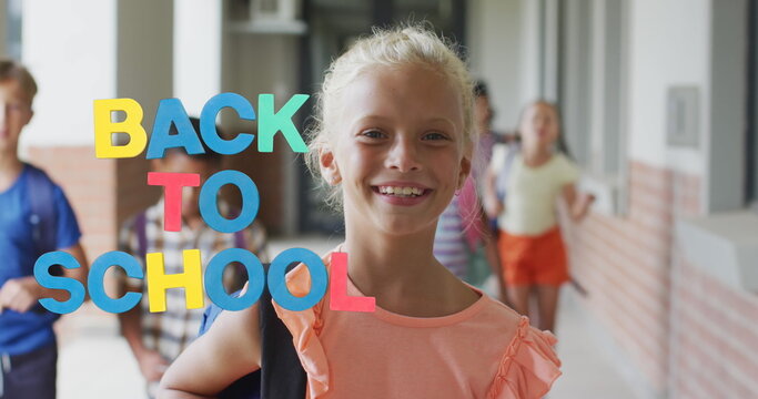 Image of colourful back to school text over smiling caucasian schoolgirl in school corridor