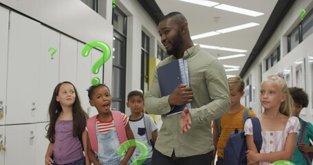Image of green question marks over happy african american male teacher and pupils in corridor
