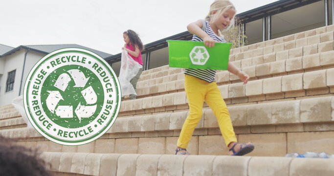 Image of recycling logo over diverse schoolgirls collecting plastic waste outside school