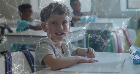 Image of networks moving over happy caucasian schoolboy working at desk class