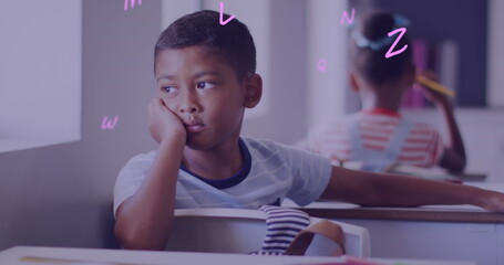 Image of letters over bored biracial schoolboy at desk in classroom - Powered by Adobe