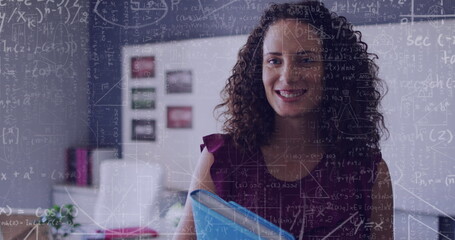 Image of maths calculations over happy biracial female teacher in classroom