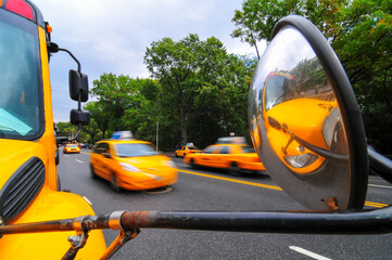 A parked school bus and speeding taxi cabs, Upper West Side Manhattan, New York City, NY, USA.