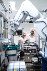 Experienced factory engineers controlling and monitoring production process of robot machines in...