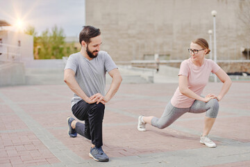 Man and woman warming up, stretching outdoors