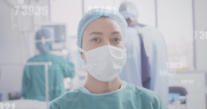 Image of medical data processing over biracial female surgeon in face mask
