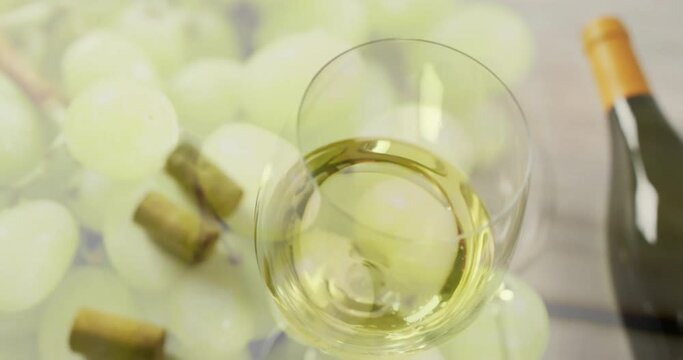 Composite of glass of white wine over corks and white grapes on white background
