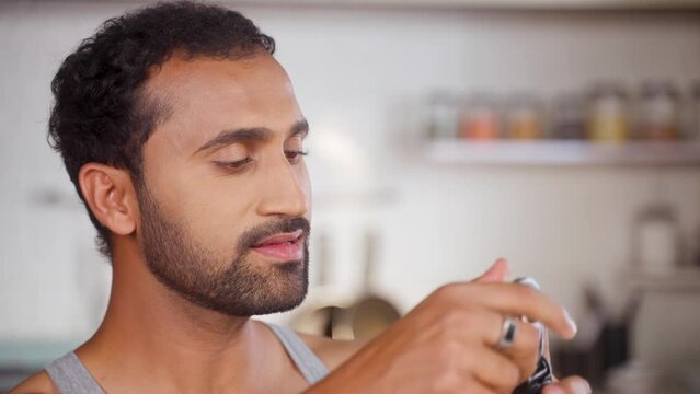 Middle aged fit man drinking protein from shaker bottle at kitchen after workout - concept of morning routine, supplement and stamina or body building