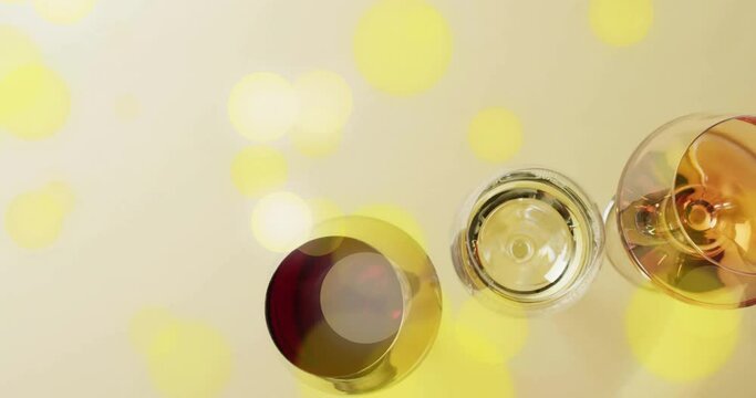 Composite of glasses of white, rose and red wine over yellow spots on yellow background