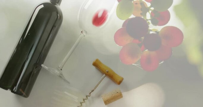 Composite of red wine bottle and glass with corcscrew over grapes background