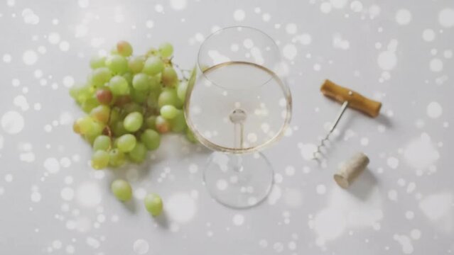 Composite of glass of white wine, grapes and corkscrew over vineyard background