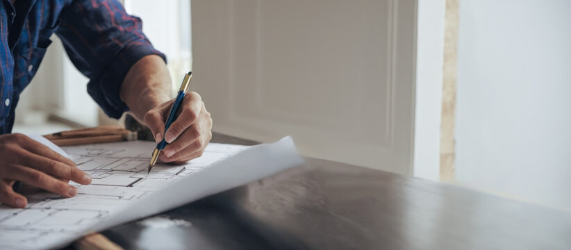 Architectural Revision Process: Close-up of expert altering residential blueprint, highlighting meticulous process of enhancing and optimizing living spaces.