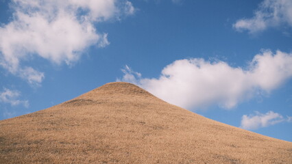 plain hill with blue sky and clouds in the background 