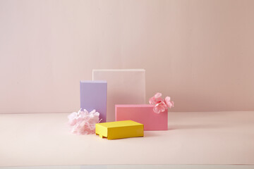 A pink and yellow, light purple square podium against light pink background. With flower. An empty platform for display cosmetic products, food and props.