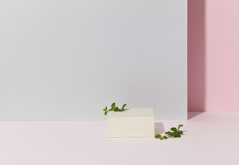 a white square podium against light pink and light grey background. With leaf. An empty platform for display cosmetic products, food and props.