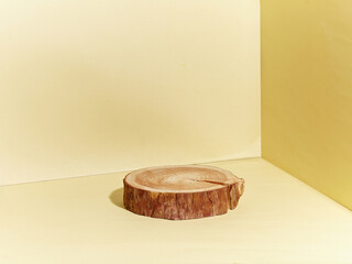 A wood circle podium against light yellow background. An empty platform for display cosmetic products, food and props.