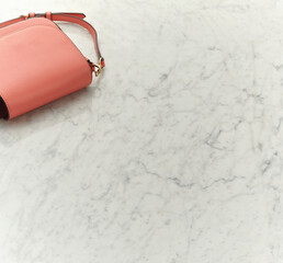 a pink bag against a white marble table background. An empty space for display cosmetic products, food and props.