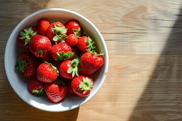 Top view of fresh red strawberries heaped in white bowl on wooden table capturing essence of summer and health ripe juicy berries offering sweet taste of nature perfect for delicious breakfast