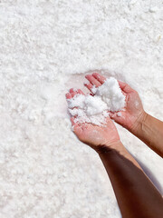 Womans hands with salt in her hands against the backdrop of salt lake.