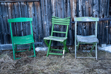 Idyllic scene: Three old, green garden chairs in front of a weathered wooden barn