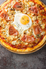 Hot delicious Pizza Bismarck with tomato sauce, melted cheese, egg, mushrooms, ham close-up on a...