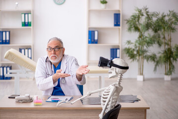Old male doctor examining skeleton in the clinic