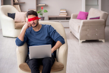 Blindfolded young male freelancer working from home