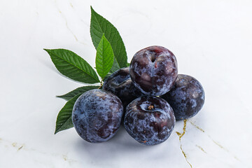 Raw purple plums heap with leaves
