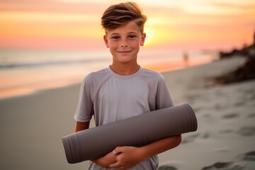 Portrait of a boy holding yoga mat on the beach at sunset
