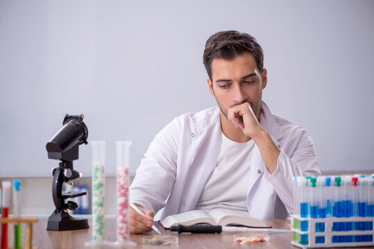 Young male chemist in front of white board - Powered by Adobe