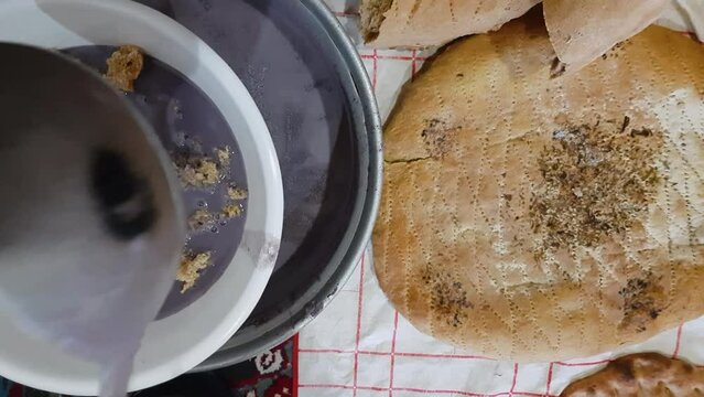 serve purple grey color vegetarian liquid food in clay bowl traditional qurut kashk local food in Khorasan rural village countryside in Iran desert climate flat bread tasty delicious Persian cuisine
