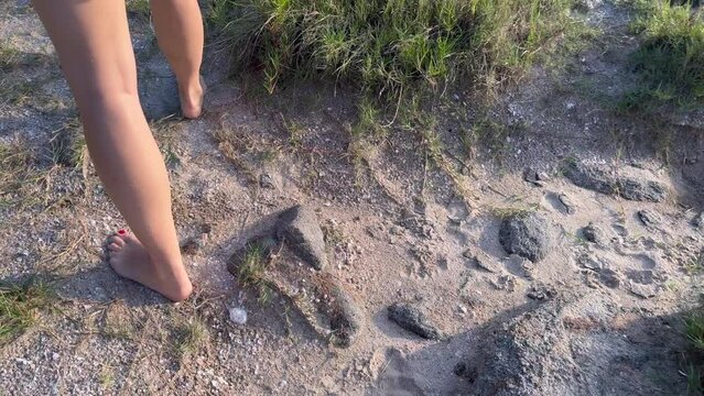 Walking barefoot between sand and rocks on a wild island