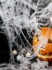 Carved pumpkin for Halloween with white spider web with black spiders, with candlelight