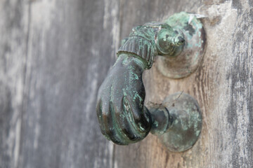 Fototapeta na wymiar Antique old bronze door knocker in shape of a hand in ancient house