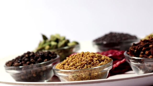 Dried spices together in glass bowl table top spin close up.