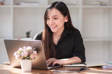 Smiling businesswoman successfully working on her laptop at her home office desk