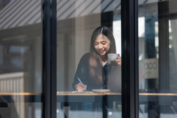Smiling businesswoman talking on the phone in her office, standing near a window and looking beautiful